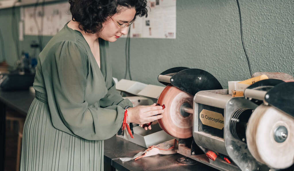 Étudiante du Bachelor Lunetier Créateur polissant une monture de lunettes à la main dans l’atelier de l’Institut Supérieur d’Optique